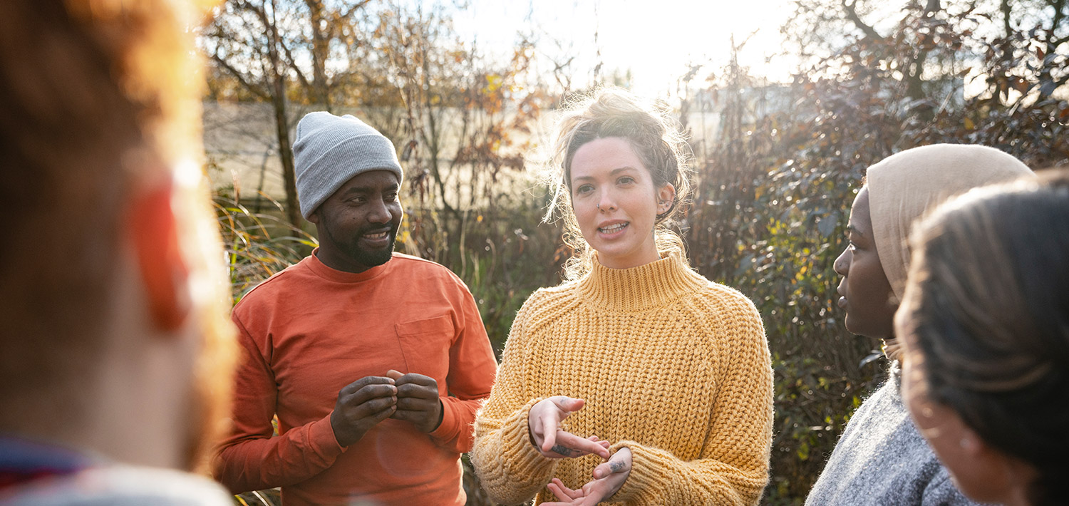 Woman in a yellow sweater talking to a group